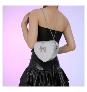 Close-up of heart-shaped silver laser PU leather crossbody bag with rhinestone bow