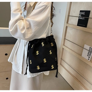 Détail du sac seau noir en toile avec signes dollar dorés et bandoulière réglable