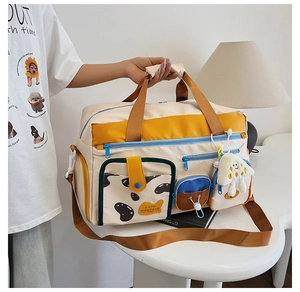 Detail einer Nylon-Reisetasche im Color-Block-Design mit süßem Anhänger und Hello Weekend Label