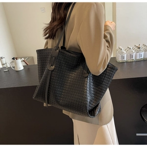 Close-up of black woven PU leather tote bag showing intricate texture and shoulder strap