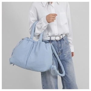 Close-up of a light blue quilted nylon handbag styled with a white shirt and jeans