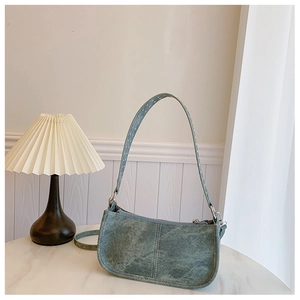 Gros plan d'un sac à bandoulière en PU métallisé avec rivets vintage sur marbre blanc