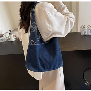 Détail du sac cabas en jean bleu avec broderie rose blanche dans un café chic