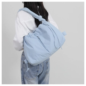 Detail of light blue padded nylon crossbody bag showing size and drape on a model back