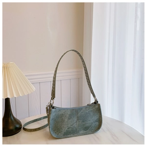 Vue détaillée d'un sac baguette vert vintage avec texture usée sur marbre blanc brillant