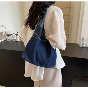 Gros plan de la broderie rose blanche sur un sac fourre-tout en denim bleu foncé