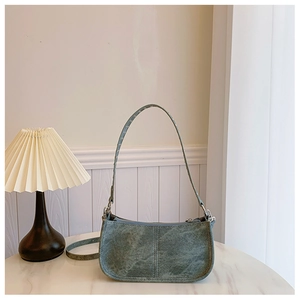 Gros plan d'un sac à bandoulière vert foncé en similicuir mat vintage sur table en marbre