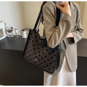 Polished brown tote bag with black polka dots and metallic bow detail on casual outfit