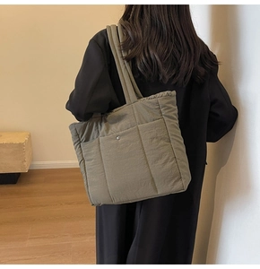Quilted olive green tote bag showing large capacity and stylish metal snap pocket detail