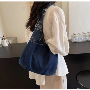 Gros plan détaillé de la broderie de rose blanche sur la bandoulière en jean bleu