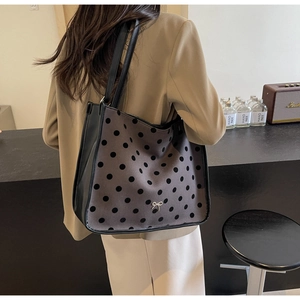 Detail of grey tote bag with black polka dots and silver bow buckle on the bottom