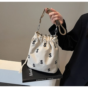 Détail du sac seau en toile blanc cassé avec broderie dollar noire et crochet en métal argenté