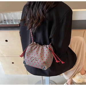 Detail of grey fabric bucket bag with red heart pattern and silver bow decoration