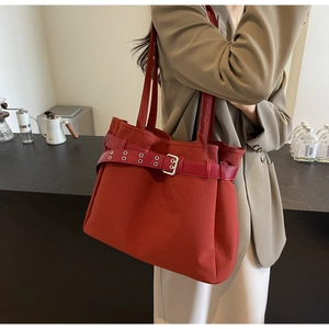 Detail view of brick red tote bag with decorative metal eyelet belt on high quality canvas
