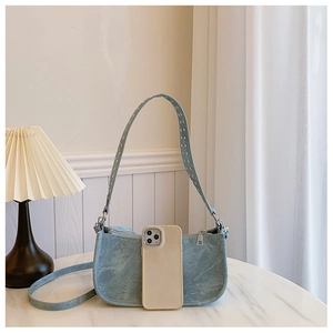 Sac à bandoulière bleu clair en forme de croissant avec détails argentés et un smartphone