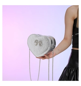 Detail of silver heart shaped bag with metallic texture and sparkling rhinestone bow