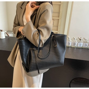 Detail of black woven PU leather tote bag showing intricate braided texture and long straps