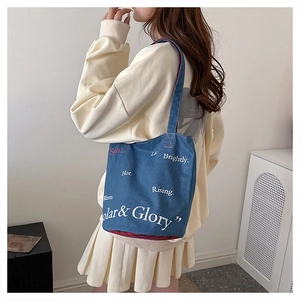 Détail du sac cabas en denim bleu avec typographie artistique et doublure à carreaux