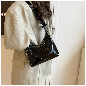 Détail du sac à bandoulière en cuir verni noir avec motif matelassé et rivets argentés