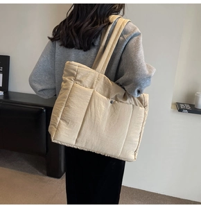 Detailed view of beige quilted tote bag with wide shoulder strap and magnetic closure