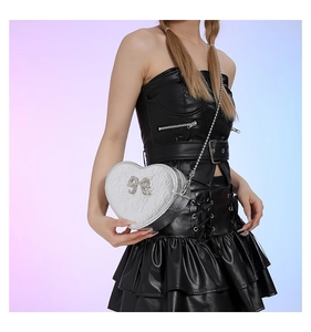 Detail of silver heart-shaped crossbody bag with glitter finish and bow decoration