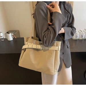 Detail of a large khaki fabric tote bag with buckle strap on a grey blazer outfit
