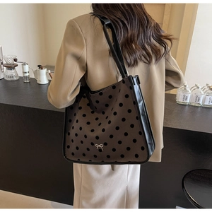 Detail of coffee brown tote bag with black polka dots and a silver bow ornament