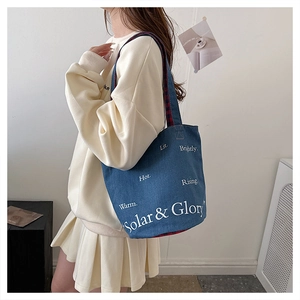 Détail du sac cabas en toile denim bleue avec typographie blanche pour usage quotidien