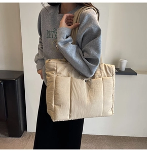 Detail of beige quilted puffer tote bag featuring three front pockets and metal buckle closure