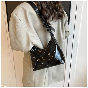Détail du sac en cuir verni noir matelassé avec clous argentés et bandoulière nouée