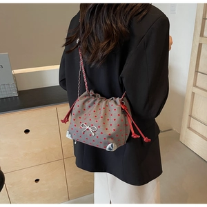Detail of grey bucket bag with red heart print and silver metal bow decoration