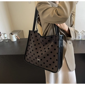 Detail of coffee brown tote with black polka dots and black leather handles shown on model