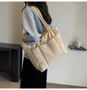 Close-up of beige quilted tote bag showing large front pockets with silver magnetic snaps