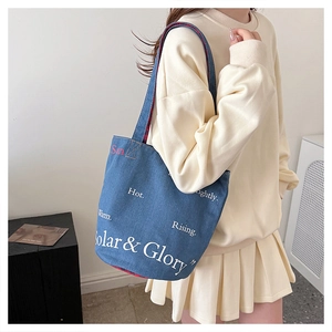 Vue détaillée du sac cabas en denim bleu foncé avec typographie et doublure à carreaux