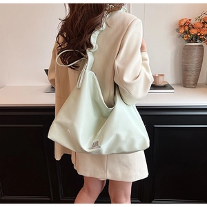 Detail of mint green PU leather shoulder bag featuring unique ruffled strap and logo