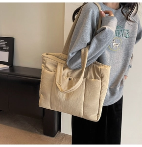 Close-up of beige quilted tote bag showing multi-pockets and lightweight puffy fabric texture
