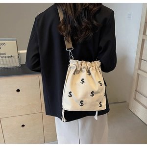 Détail d'un sac seau en toile écru avec broderie dollar et large bandoulière
