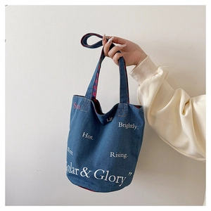 Détail du sac cabas en denim bleu avec doublure à carreaux rouges et texte blanc