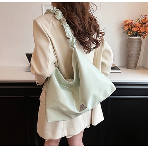 Detail of mint green PU leather shoulder bag with ruffled strap and metal logo