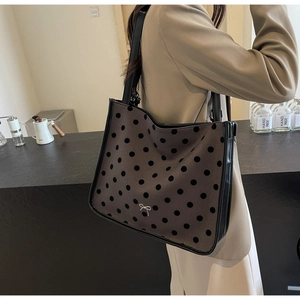 Polka dot fabric tote bag with silver bow detail shown on shoulder in a cafe setting