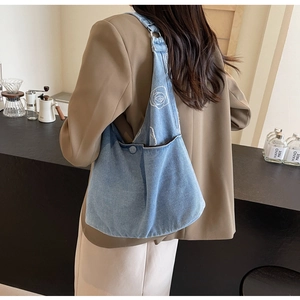Détail du sac bandoulière en denim bleu clair avec broderie rose blanche sur un modèle