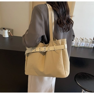 Detail of a large khaki commuter tote bag featuring a decorative silver metal buckle