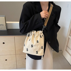 Détail du sac seau en toile avec broderie de signe dollar noir et bandoulière