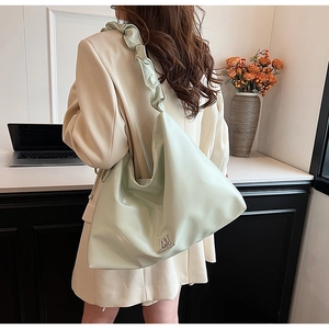 Detail of mint green PU leather shoulder bag with ruffled strap and metal logo