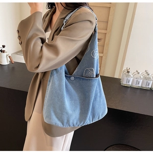 Détail du sac cabas en jean bleu clair avec broderie rose blanche élégante et bandoulière large