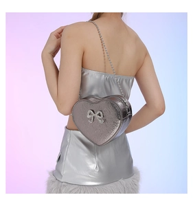 Close-up of heart-shaped silver PU leather crossbody bag with a sparkling diamond bow