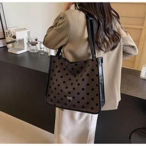 Close-up of a brown tote bag with black polka dots and a silver metal bow detail