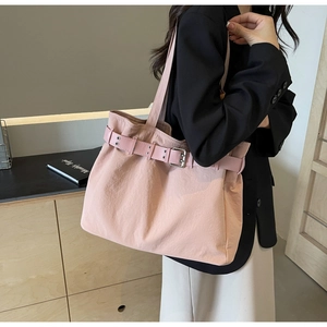 Detail of pink fabric tote bag showing decorative belt strap and metal eyelet accents