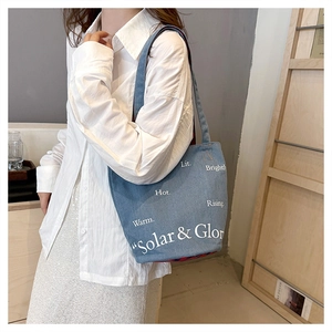 Détail du sac cabas en denim avec imprimé lettres et doublure à carreaux rouge et bleu