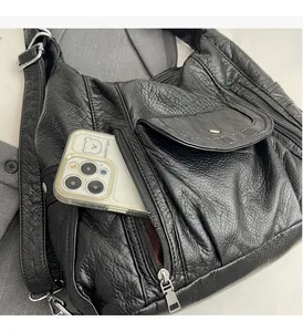 Detail of black PU leather bag showing spacious functional pocket with a smartphone inside